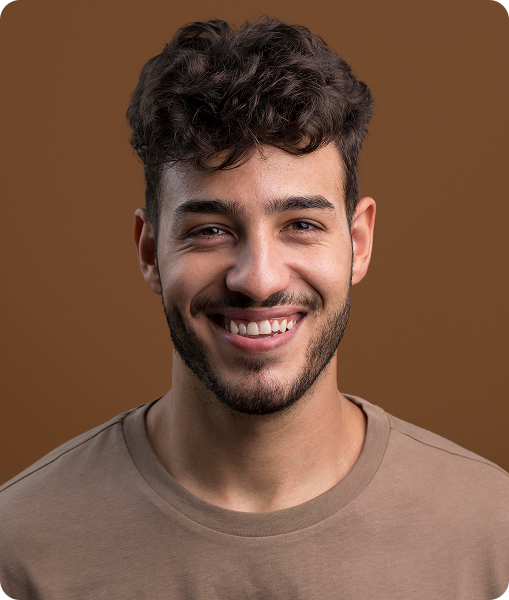 Man with curly hair and beard wearing brown t-shirt smiling